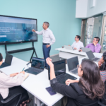 Professional team engaged in a business presentation with laptops and a projector screen.